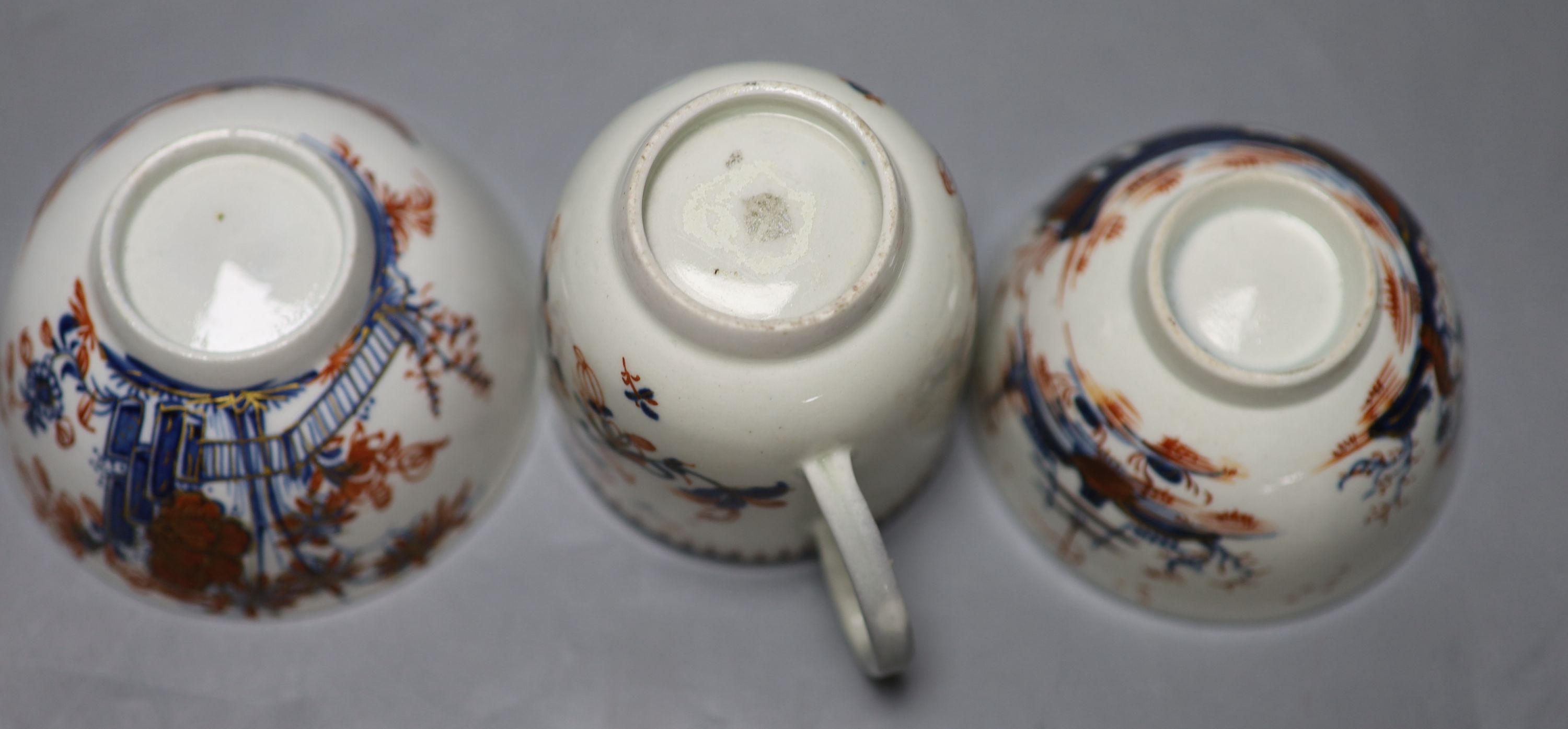 An 18th century Liverpool coffee cup and two teabowls, painted in blue with overglaze red highlights